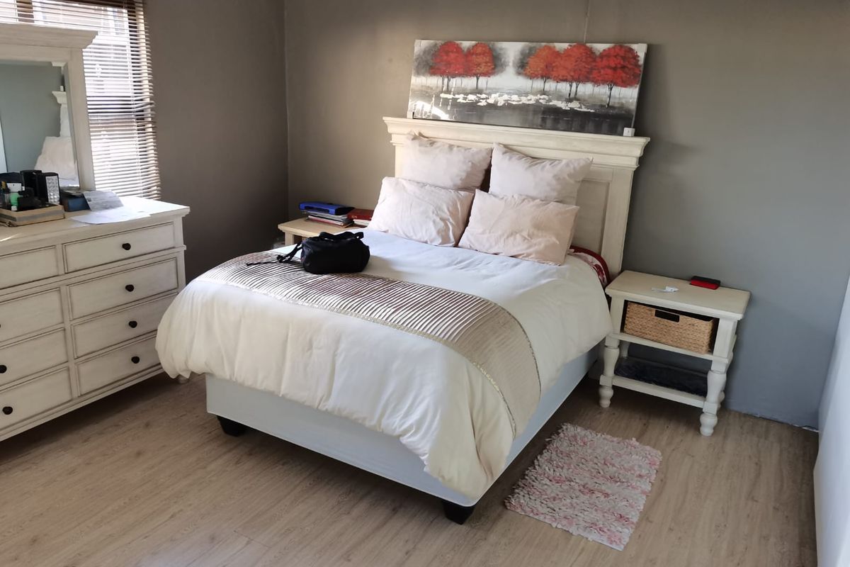 A bedroom featuring light-toned laminate flooring and venetian blinds, providing a neutral foundation for personal styling.
