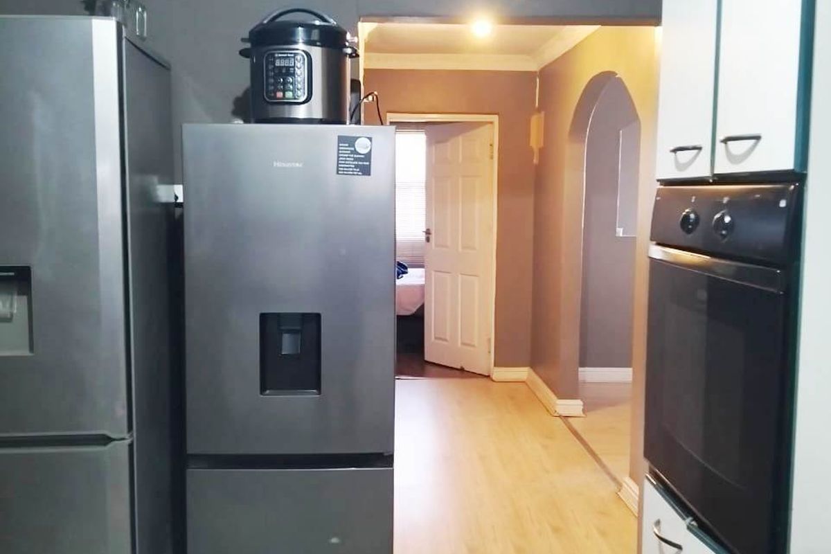 Kitchen area featuring built-in oven and cabinetry, leading through an archway into an adjacent room with laminate flooring.