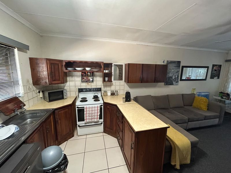 Open-plan kitchen and living area featuring traditional wooden cabinetry, laminate countertops, and a freestanding stove, offering a functional layout for daily living.