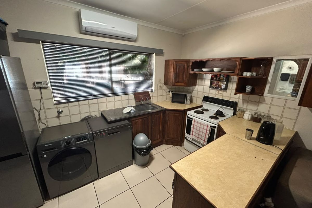Functional kitchen featuring wooden cabinetry, laminate countertops, tiled backsplash, and integrated space for laundry appliances, offering a practical layout for daily use.