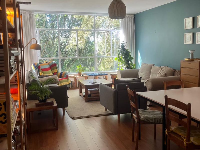 Spacious open-plan living and dining area featuring large windows that provide ample natural light and views of the surrounding greenery.