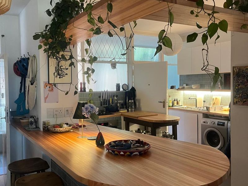 Modern open-plan kitchen featuring a custom timber breakfast bar, tiled island base, and integrated cabinetry with a functional laundry area.