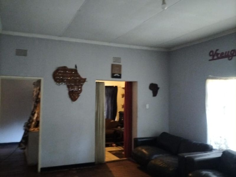 A living room featuring timber flooring and ceiling vents, providing a functional space with potential for cosmetic updates.