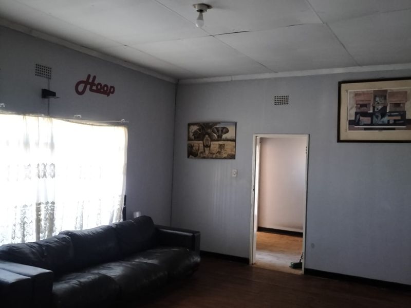 A living room featuring timber flooring and ceiling tiles, providing a basic foundation for renovation and interior design updates.