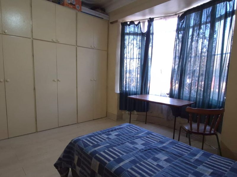 A bedroom featuring extensive built-in cupboards and a bay window, providing ample storage and natural light.