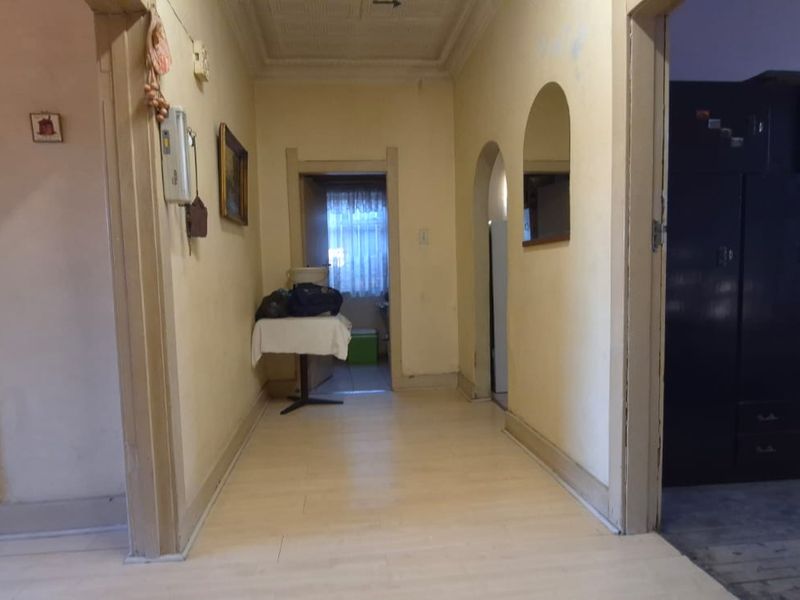 A central hallway featuring arched doorways, laminate flooring, and decorative ceiling tiles, providing access to multiple rooms within the home.