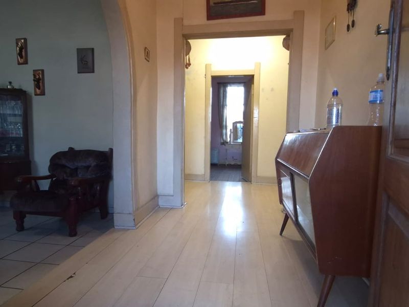 A view through a central hallway featuring timber flooring and an arched entryway leading to adjacent living spaces.