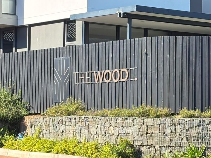 Front elevation of the property featuring a modern gabion retaining wall, timber slat fencing, and paved driveway entrance.