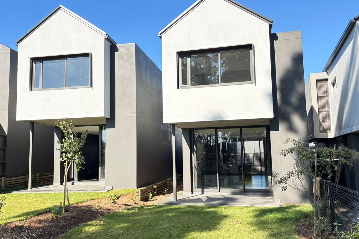 Modern double-storey residential units featuring clean architectural lines, large sliding glass doors, and private ground-floor patios overlooking a landscaped garden area.