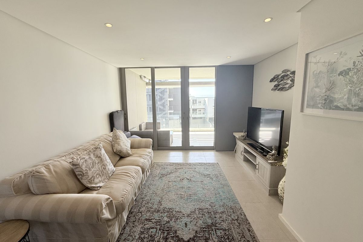 A bright living room featuring tiled flooring, recessed downlighting, and large sliding glass doors providing access to an outdoor balcony area.