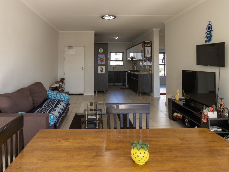 Open-plan living and kitchen area featuring tiled flooring, modern dark cabinetry, and a functional layout suitable for dining and relaxation.