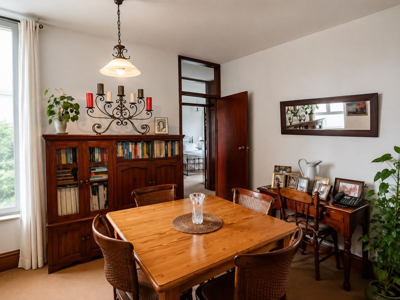 A well-maintained dining room featuring neutral carpeting, classic timber door frames, and a central pendant light fixture, offering a warm and inviting atmosphere.