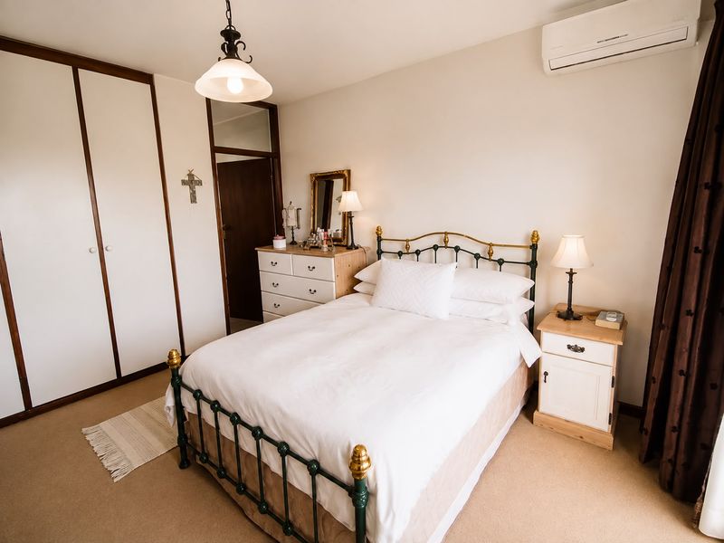 A well-maintained bedroom featuring built-in wardrobes, carpet flooring, and a wall-mounted split-system air conditioner for climate control.