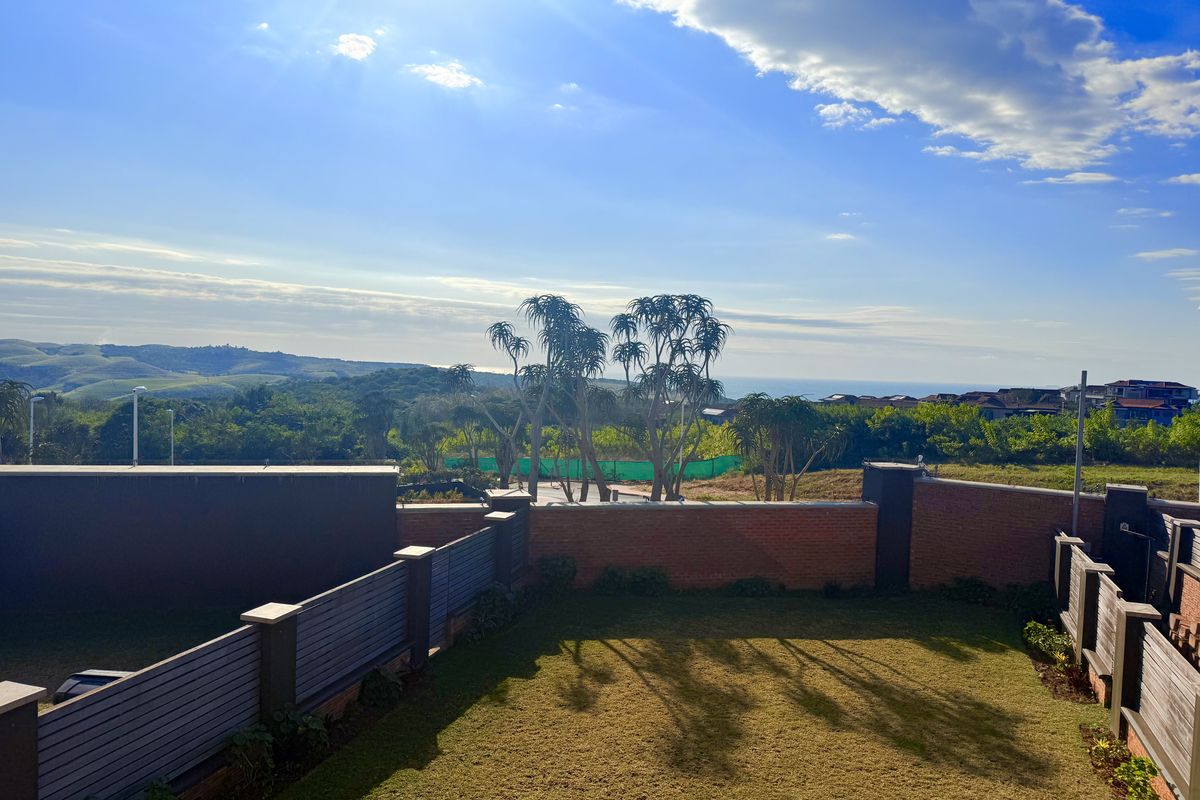A well-maintained rear garden featuring a brick boundary wall with timber slat fencing and expansive views of the surrounding landscape.
