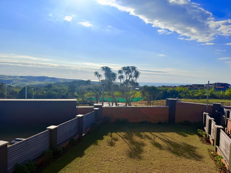 A well-maintained rear garden featuring a brick boundary wall with timber slat fencing and expansive views of the surrounding landscape.