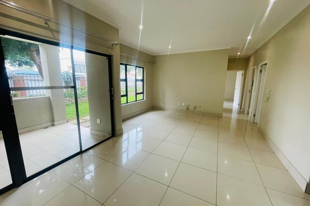 Spacious, light-filled living area featuring neutral tiled flooring, recessed lighting, and a sliding glass door providing direct access to the patio.