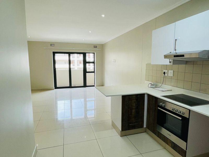 An open-plan living and kitchen area featuring modern tiled flooring, built-in cabinetry, and sliding glass doors leading to an outdoor space.