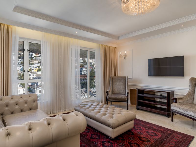 Elegant living room featuring crown molding, wainscoting, stone flooring, and large windows with balcony access, offering a bright and sophisticated atmosphere.