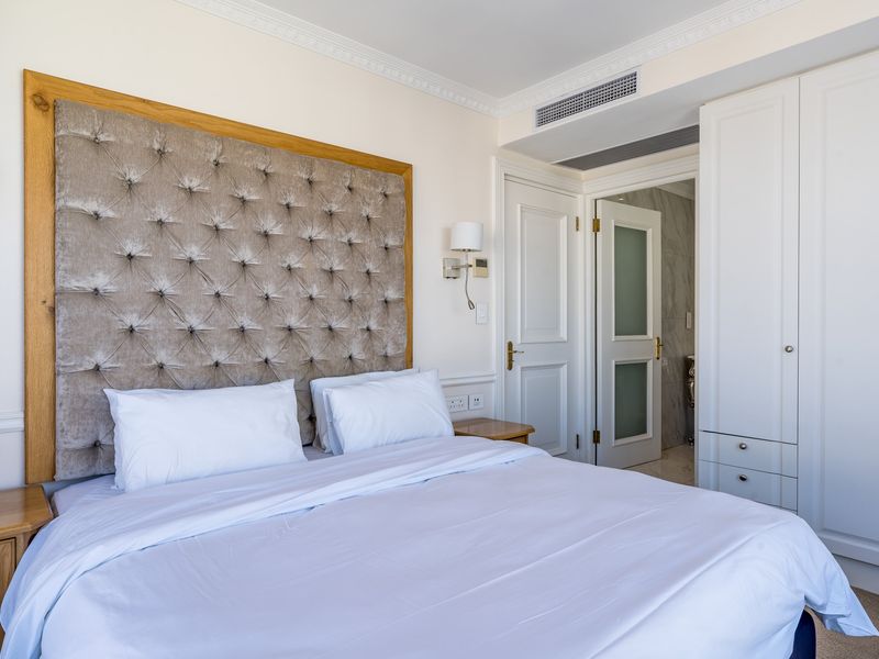 A well-maintained bedroom featuring built-in wardrobes, crown molding, ducted air conditioning, and an en-suite bathroom access.