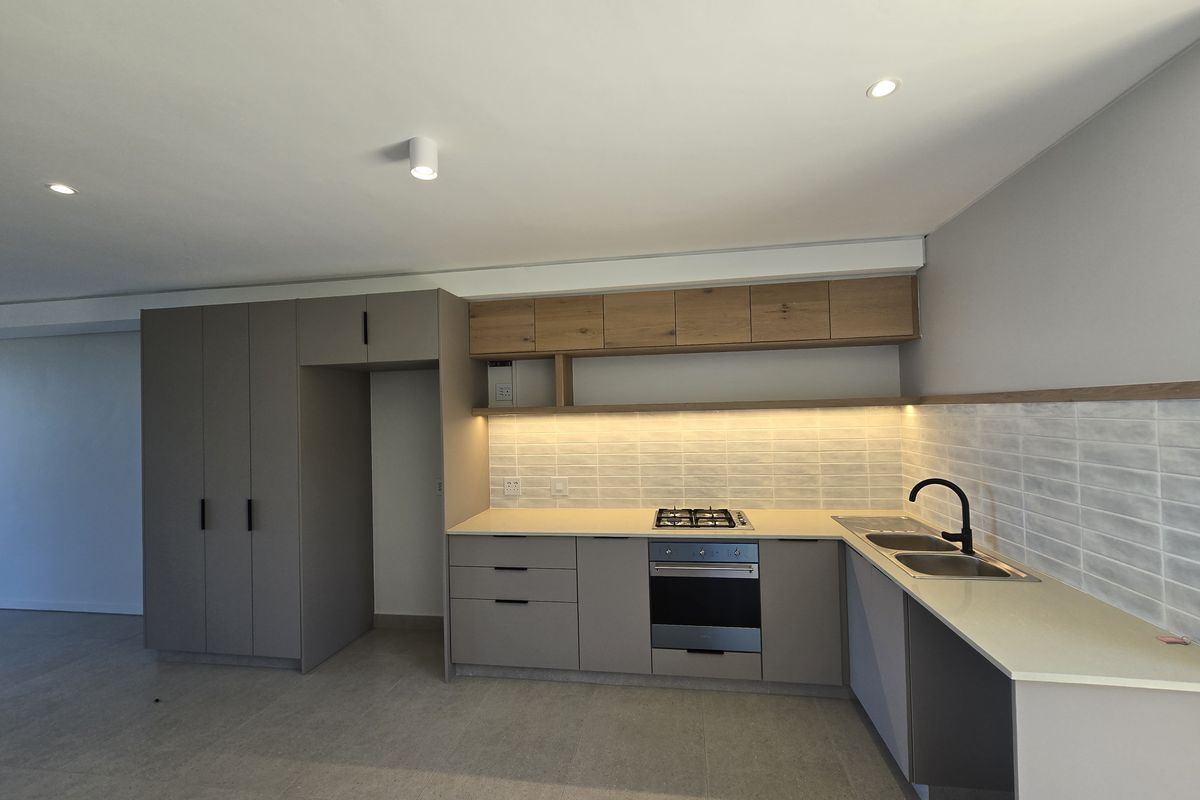 Modern kitchen featuring sleek cabinetry, stone countertops, integrated gas hob, electric oven, and a double sink with contemporary fixtures.