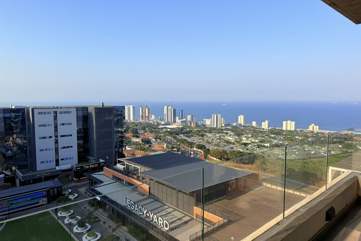 Elevated panoramic view overlooking the coastal urban landscape, ocean, and surrounding commercial developments from a modern balcony.