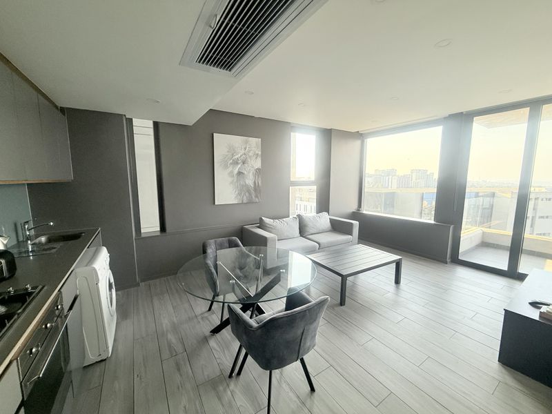 Modern open-plan living area featuring a sleek kitchen, tiled flooring, ducted air conditioning, and floor-to-ceiling windows with access to a private balcony.