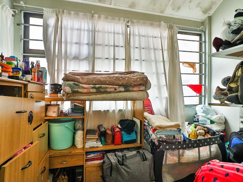 A bedroom featuring security bars on the windows and visible water damage on the ceiling requiring maintenance.