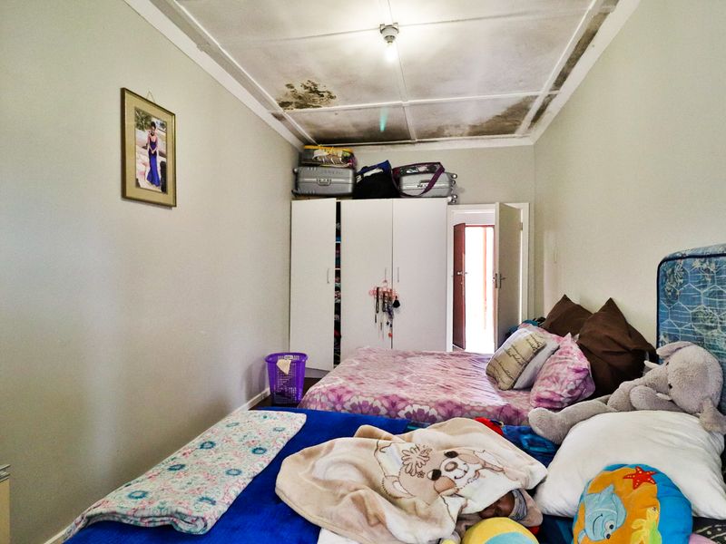 A bedroom featuring a built-in wardrobe and visible water damage on the ceiling tiles, indicating a need for maintenance and repair.