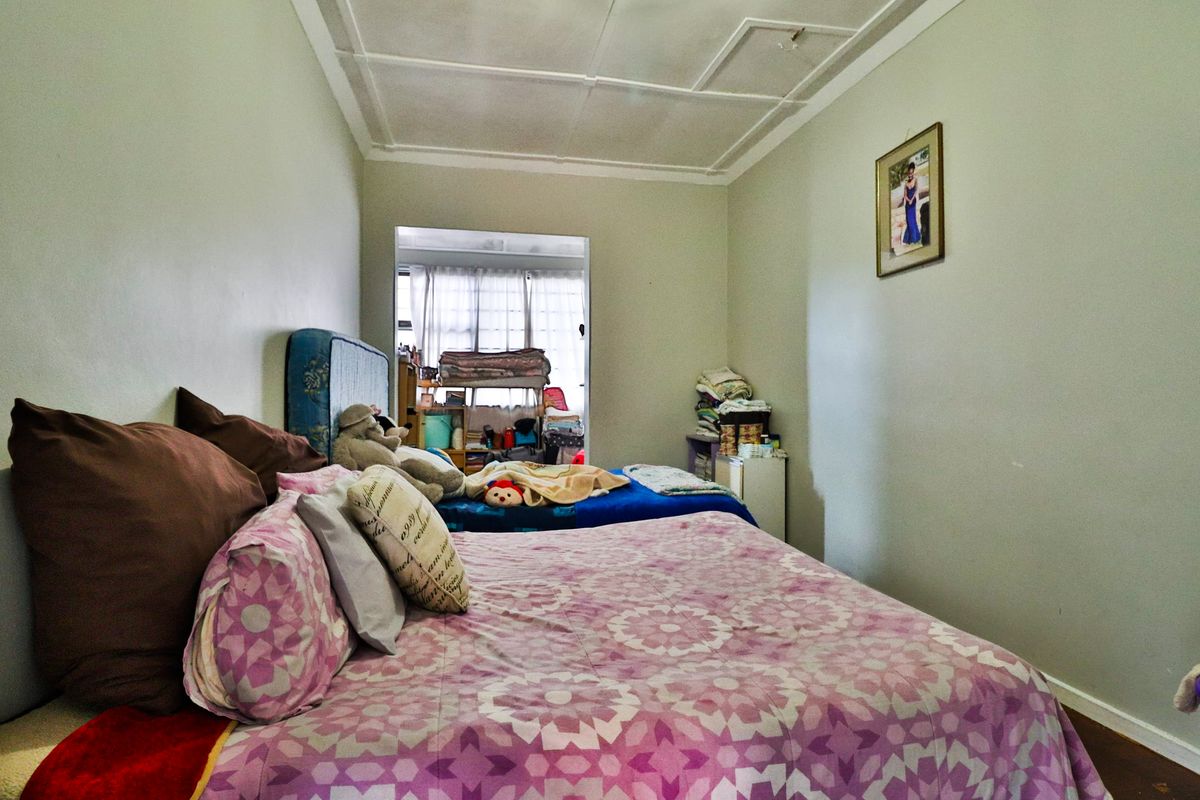 A bedroom featuring traditional ceiling detailing and timber flooring, requiring cosmetic updates to improve the overall finish and appeal.