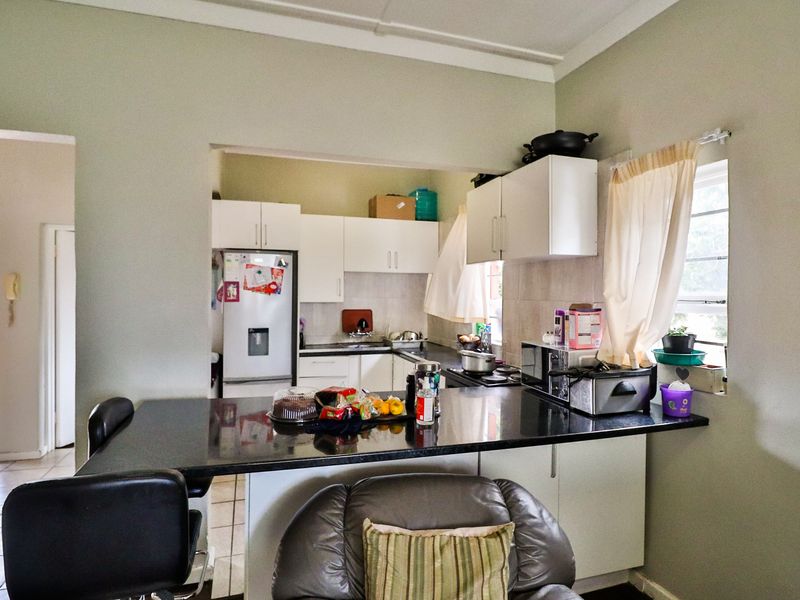 Open plan kitchen featuring white cabinetry, dark granite countertops, and integrated cooking appliances, seamlessly connecting to the living area.