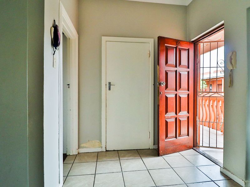 Entrance foyer featuring tiled flooring, a solid timber front door, and an integrated intercom system, providing direct access to the apartment interior.