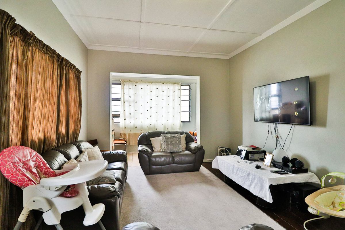 A functional living room featuring a neutral color palette, large window for natural light, and a dedicated wall space for entertainment.