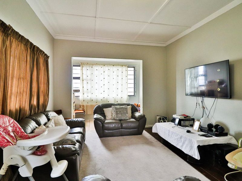 A functional living room featuring a neutral color palette, large window for natural light, and a dedicated wall space for entertainment.
