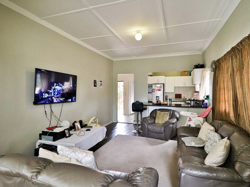 Open-plan living area featuring a combined lounge and kitchen space with hardwood flooring and tiled ceiling finishes.
