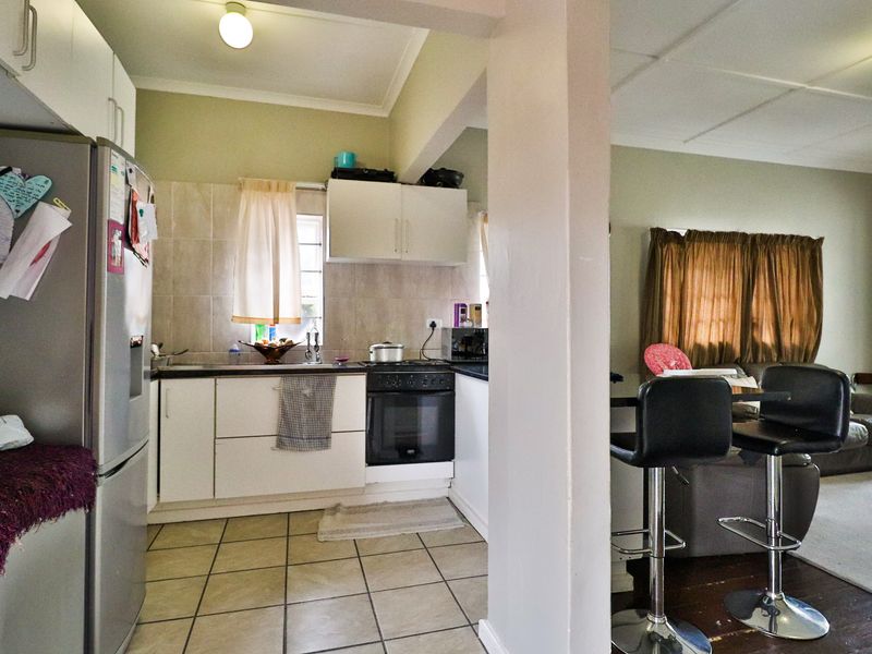 Open-plan kitchen and living area featuring tiled flooring, built-in cabinetry, and integrated oven and hob, providing a functional layout for daily living.