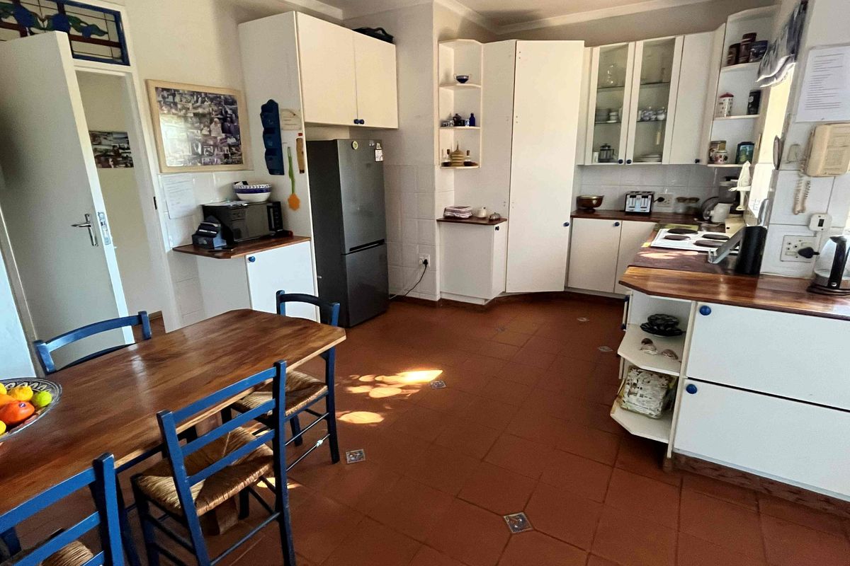 A functional kitchen featuring white built-in cabinetry, wooden countertops, and traditional terracotta floor tiles, offering a classic and practical layout.
