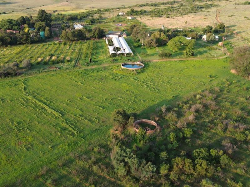 Aerial view of a farm property featuring multiple greenhouses, water reservoirs, and expansive grazing land.