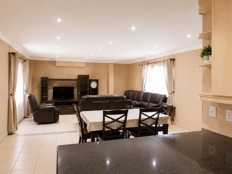 Spacious open-plan living and dining area featuring tiled flooring, recessed lighting, and a modern kitchen with granite countertops.