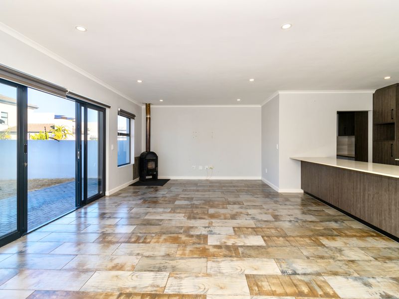 Spacious open-plan living area featuring tiled flooring, a wood-burning fireplace, and seamless access to the outdoor patio through large sliding glass doors.