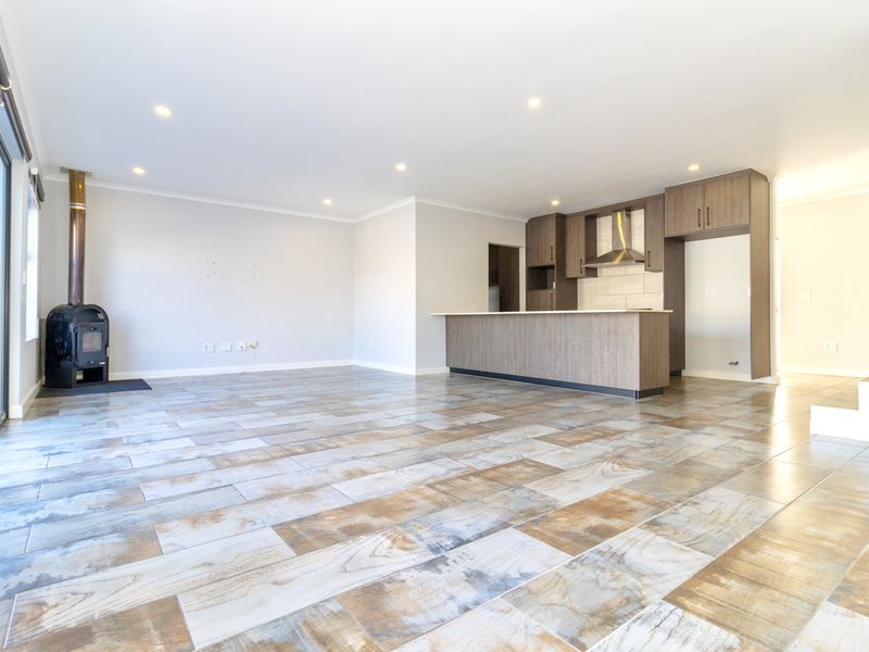 Spacious open-plan living area featuring a modern kitchen with island, wood-burning fireplace, and large sliding doors leading to the exterior.