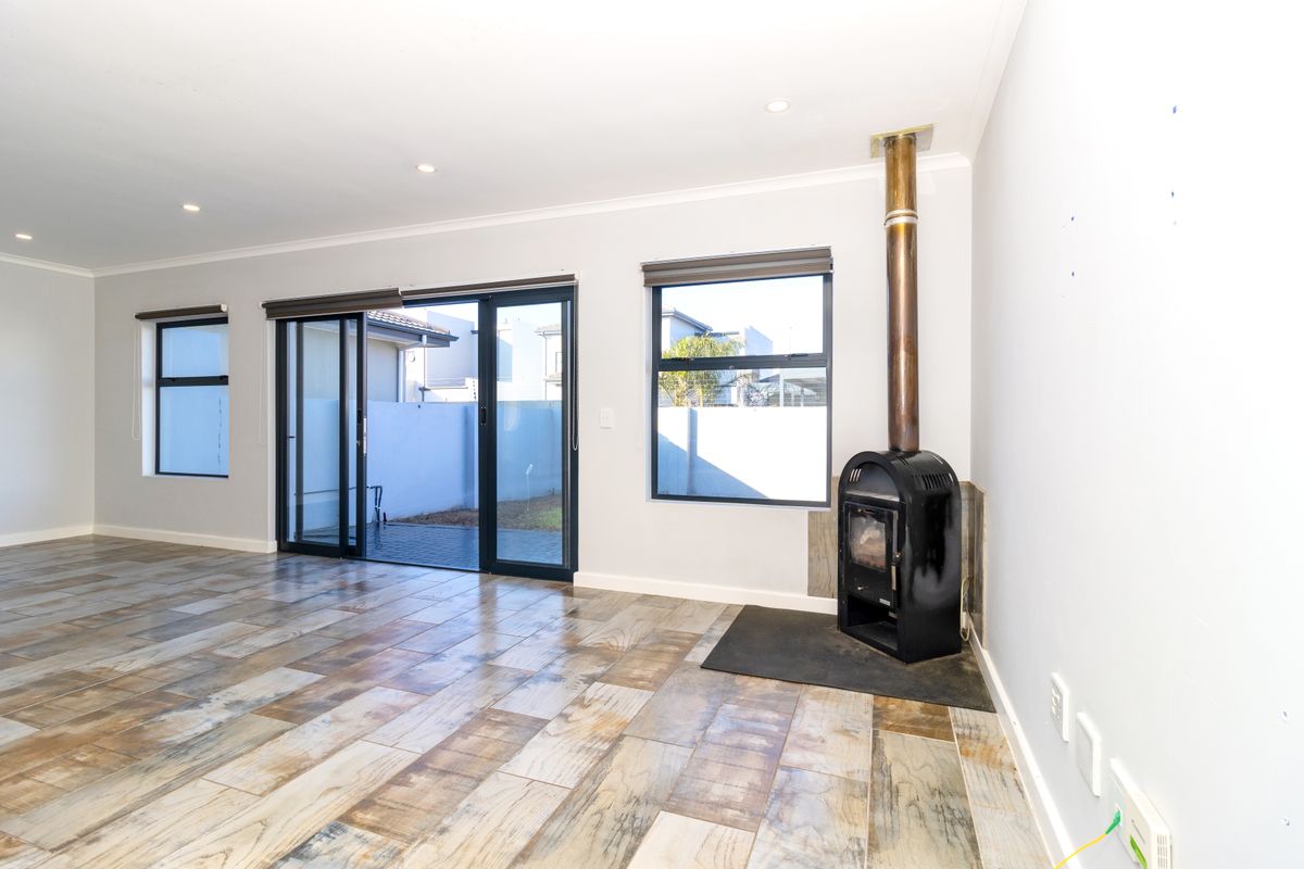 Spacious living area featuring wood-look tiled flooring, a built-in wood-burning fireplace, and sliding glass doors providing access to the outdoor area.