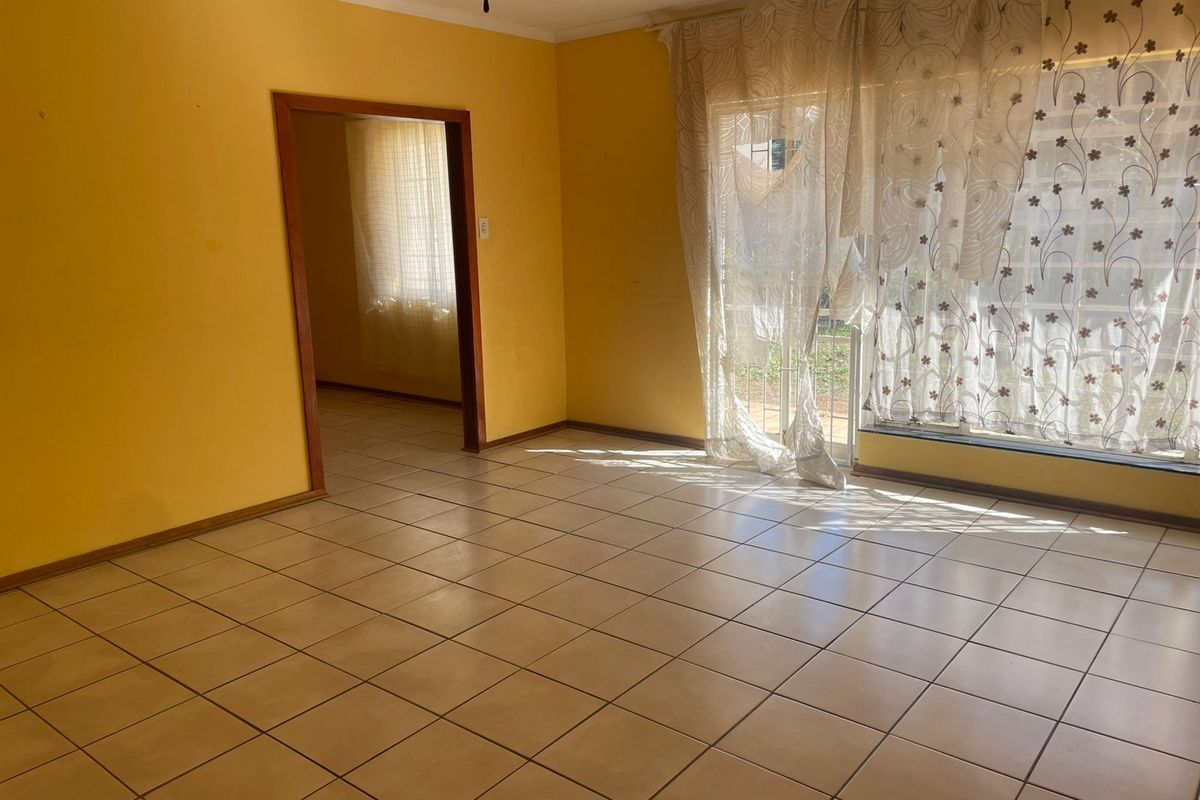 An empty living room featuring ceramic floor tiles, a timber door frame, and a ceiling fan, with access to an adjacent room.