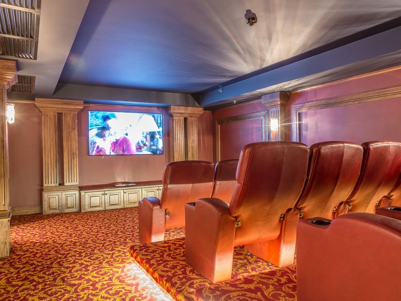 A dedicated home cinema room featuring tiered seating, decorative wall columns, built-in cabinetry, and integrated lighting.
