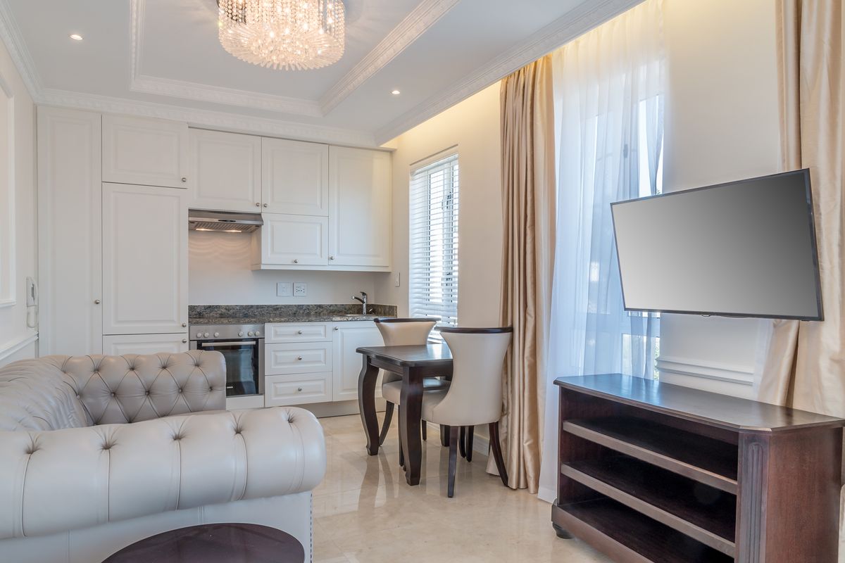 A well-appointed open-plan living and kitchen area featuring high-end cabinetry, granite countertops, marble flooring, and elegant crown molding.
