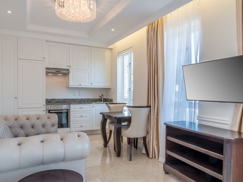 A well-appointed open-plan living and kitchen area featuring high-end cabinetry, granite countertops, marble flooring, and elegant crown molding.