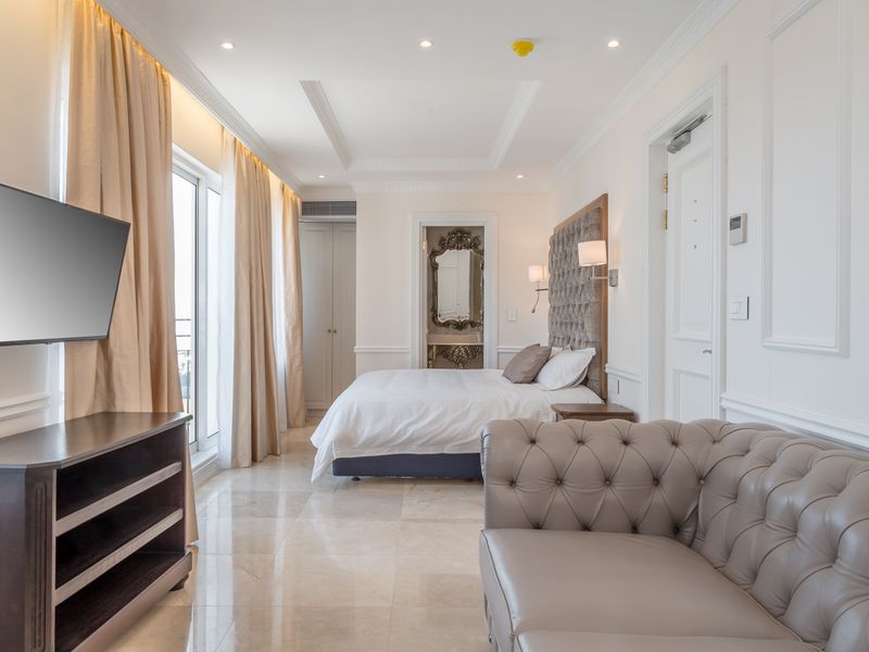 A well-appointed bedroom featuring marble flooring, crown molding, recessed lighting, and direct access to a balcony through sliding glass doors.