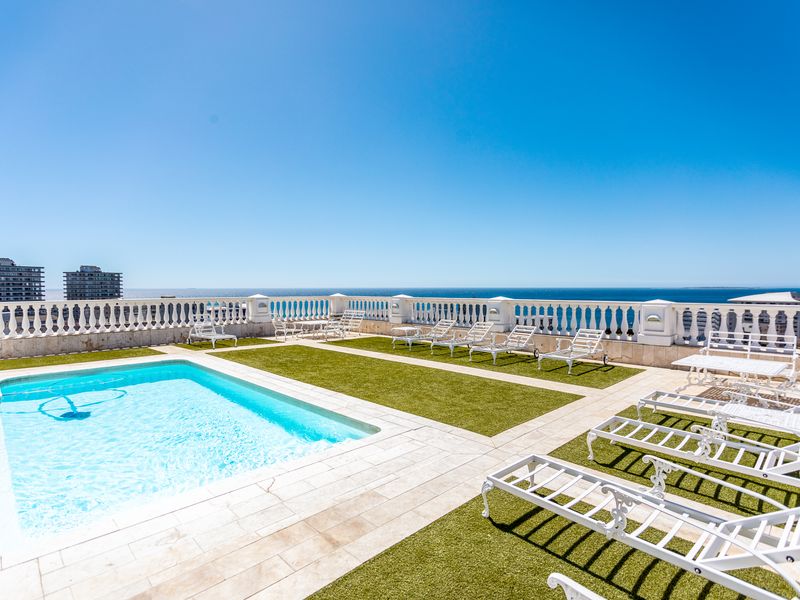 Spacious rooftop pool area featuring a swimming pool, artificial turf, and a classic balustrade with panoramic ocean views.