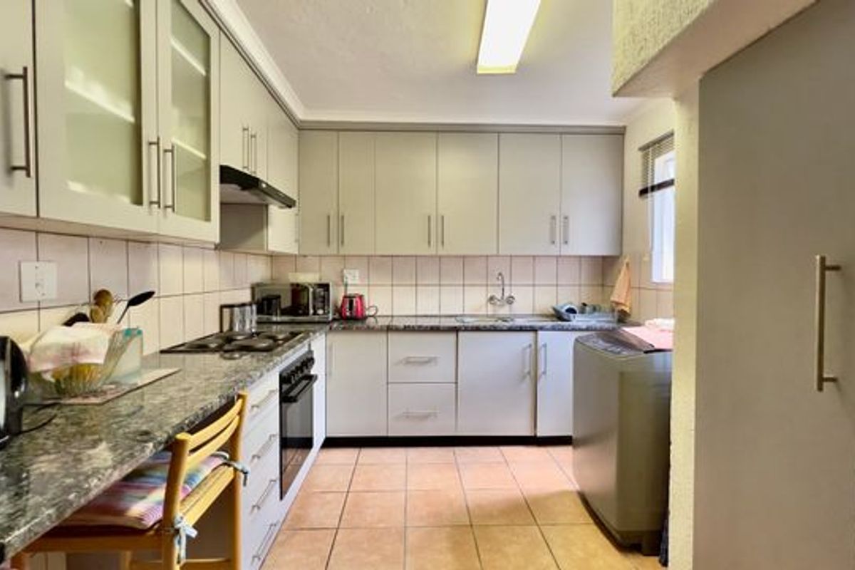 Functional kitchen featuring ample built-in cabinetry, granite countertops, a tiled backsplash, and integrated cooking appliances with tiled flooring throughout.