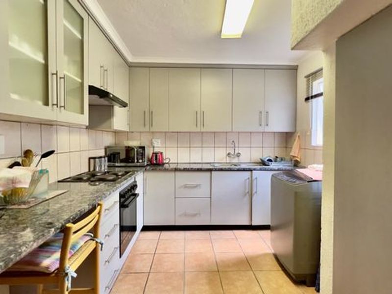 Functional kitchen featuring ample built-in cabinetry, granite countertops, a tiled backsplash, and integrated cooking appliances with tiled flooring throughout.