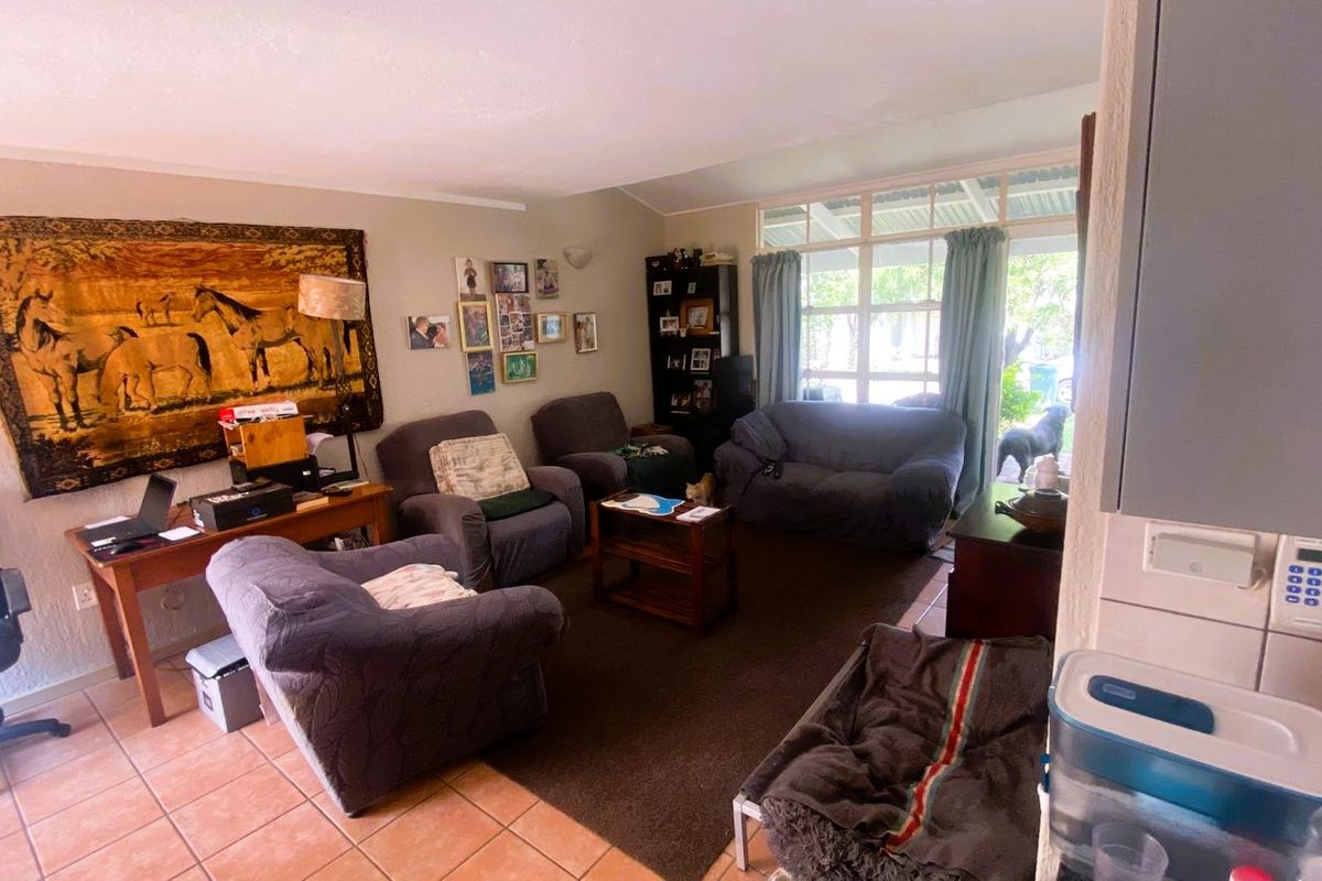 A comfortable living room featuring tiled flooring and a large glass sliding door providing natural light and access to the outdoor area.